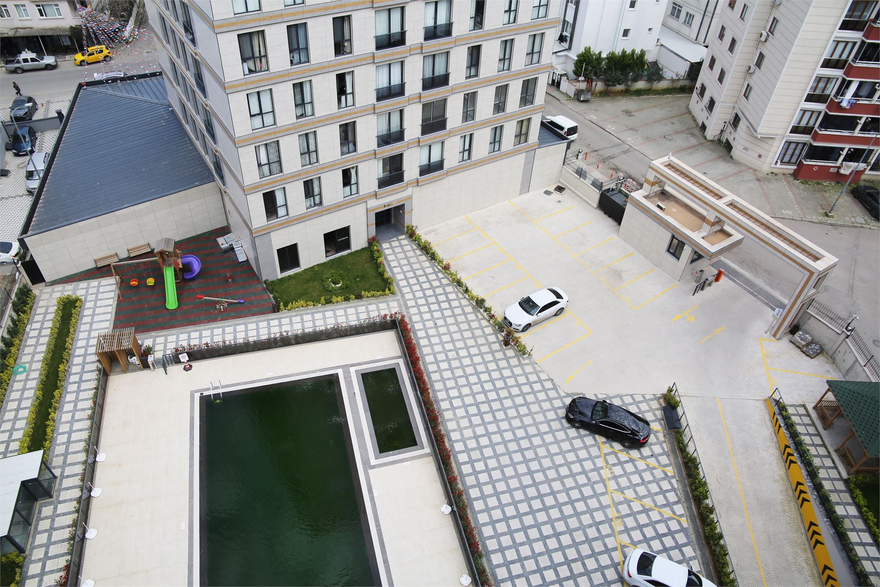 Özalp İnşaat konut projesinin havadan görünümü — süs havuzu, çocuk parkı ve otopark